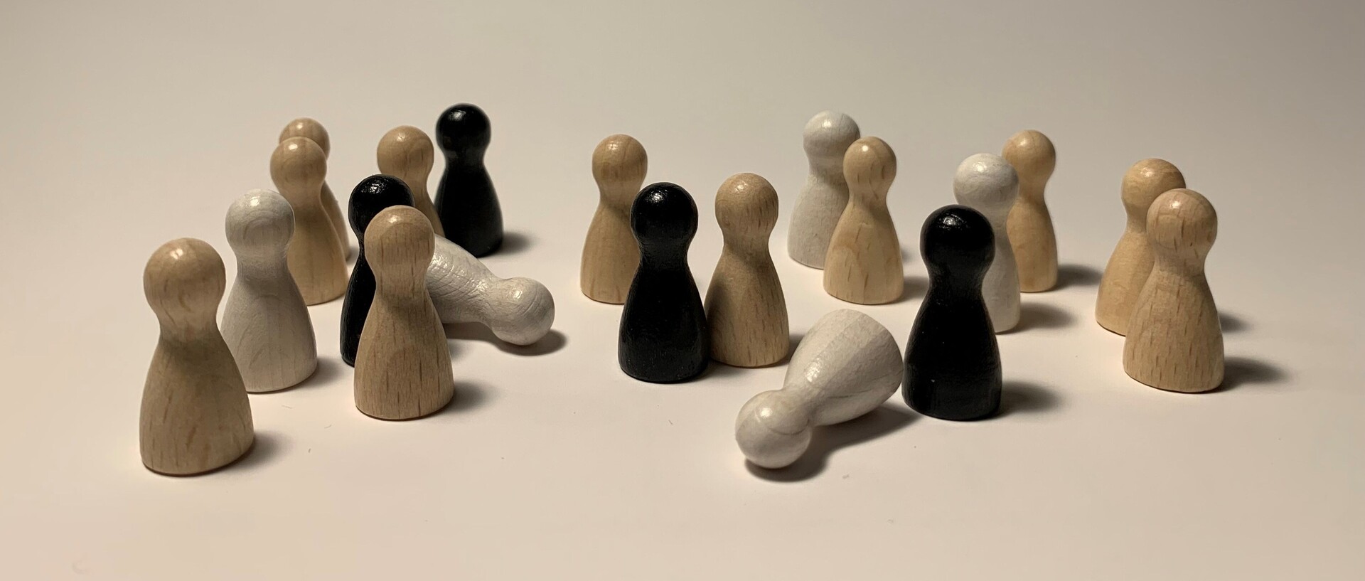 Beige, weiße und schwarze Spielfiguren sind aufgestellt. Zwei weiße Spielfiguren sind umgefallen.