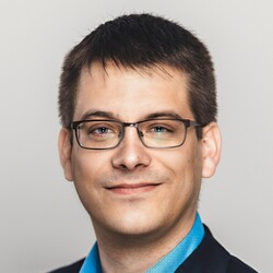 Philipp Zumstein hat kurzes braunes Haar. Er trägt eine Brille, ein blaues Hemd und ein schwarzes Jackett.