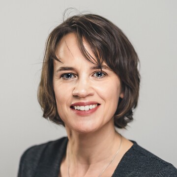 Jessica Kaiser hat kinnlanges dunkelbraunes Haar, sie trägt eine Kette und ein grau-schwarzes Oberteil.
