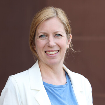 Katharina Selzer hat langes blondes Haar, sie trägt ein hellblaues Oberteil und ein weißes Jackett.