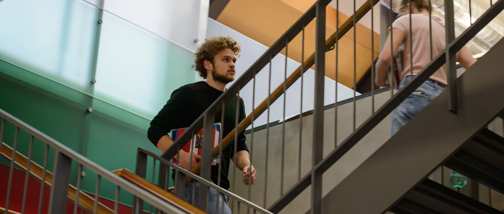 Ein Student läuft die Treppe im Bibliotheksbereich Schloss Ehrenhof hinauf.
