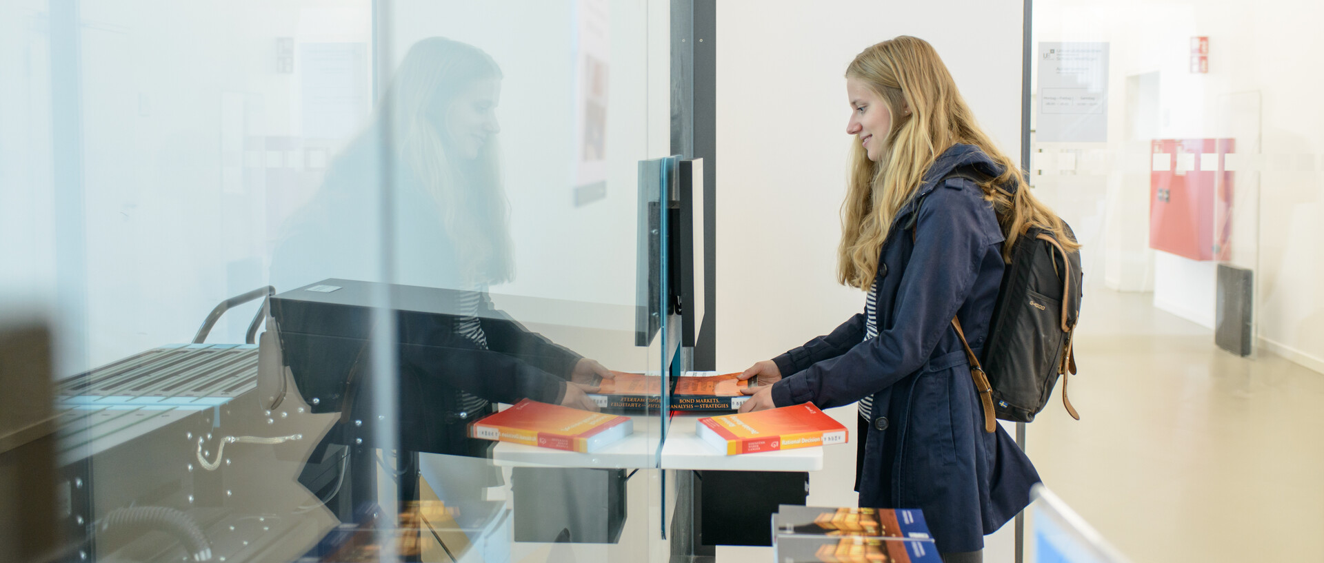 Eine Studentin gibt Bücher über die Rückgabeanlage im Ausleihzentrum Schloss Westflügel zurück.