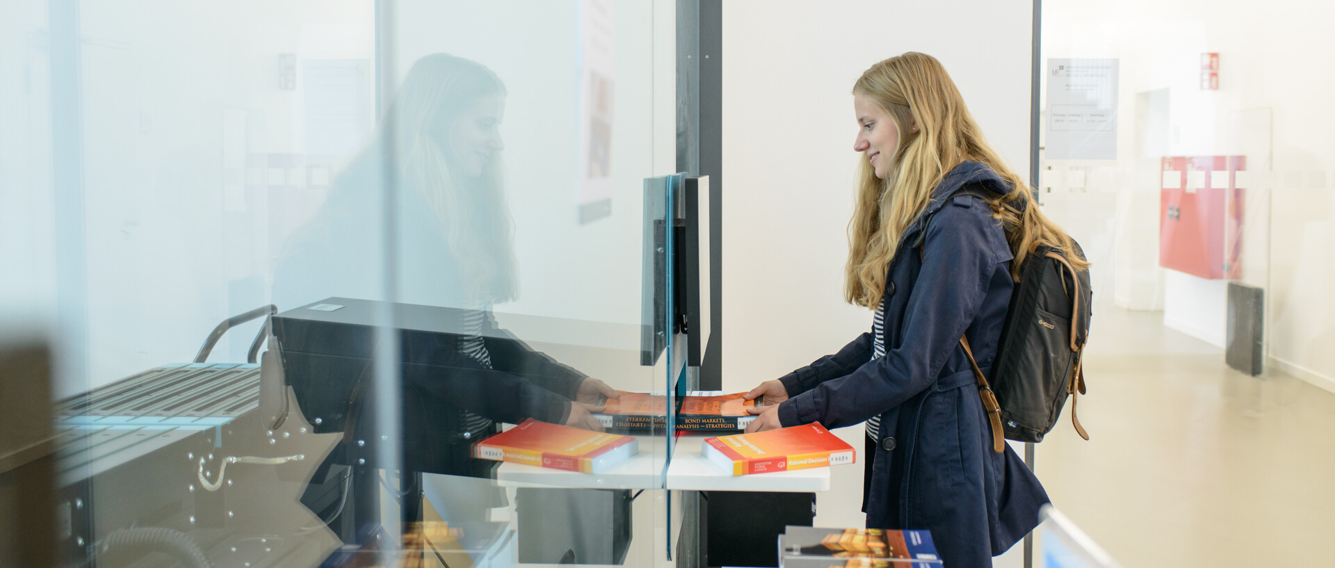Eine Studentin gibt Bücher über die Rückgabeanlage im Ausleihzentrum Schloss Westflügel zurück.