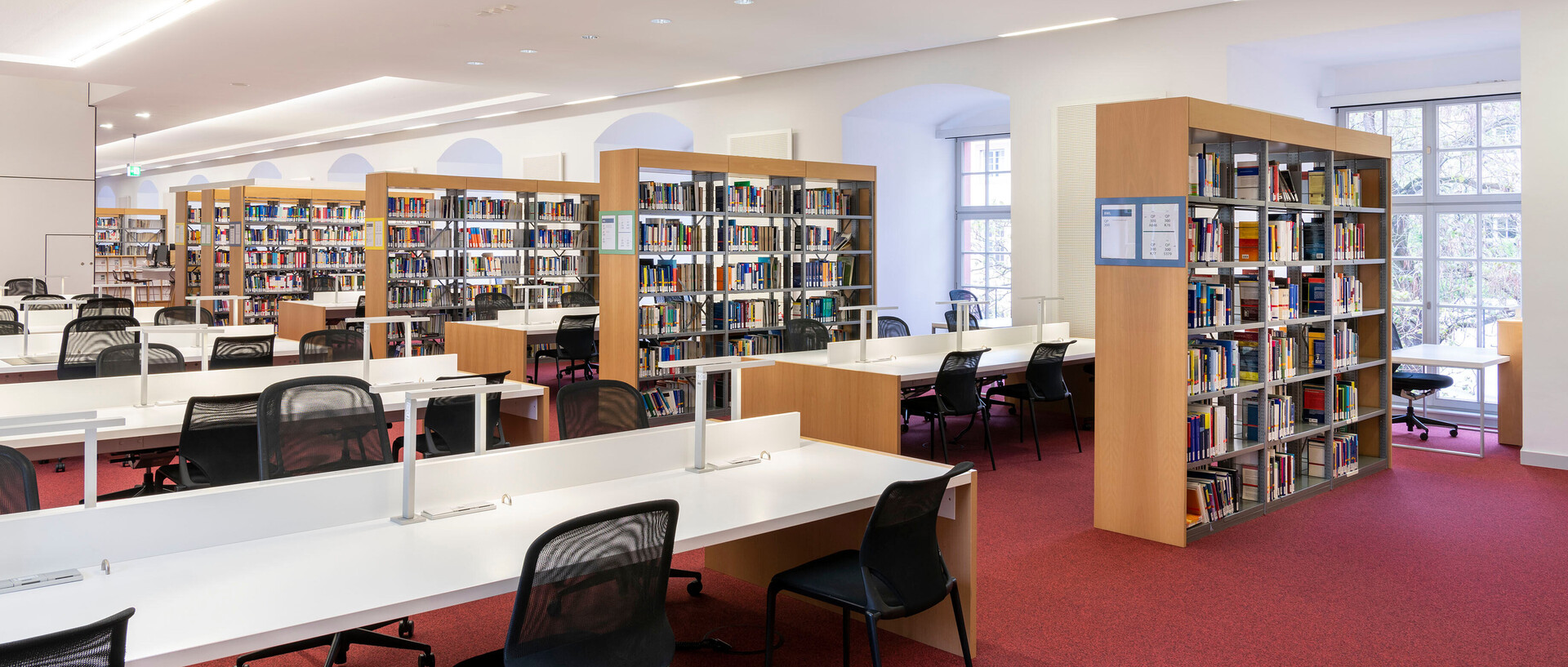 Bücherregalreihen und Arbeitsplätze im Bibliotheksbereich Schloss Schneckenhof.