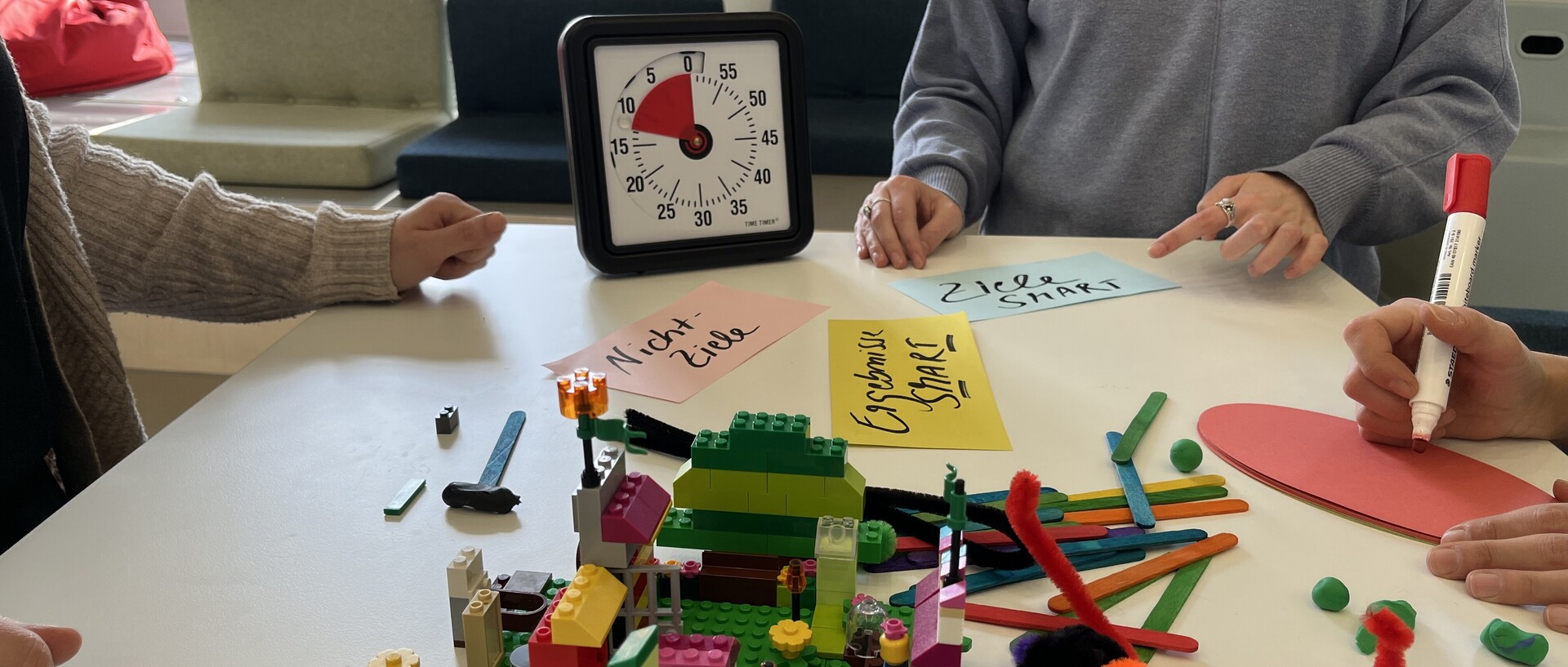 Design-Thinking-Tools im ExpLAB im Bibliotheksbereich Schloss Schneckenhof: Legosteine, Wolle, Karten, Stifte und ein großer Timer.