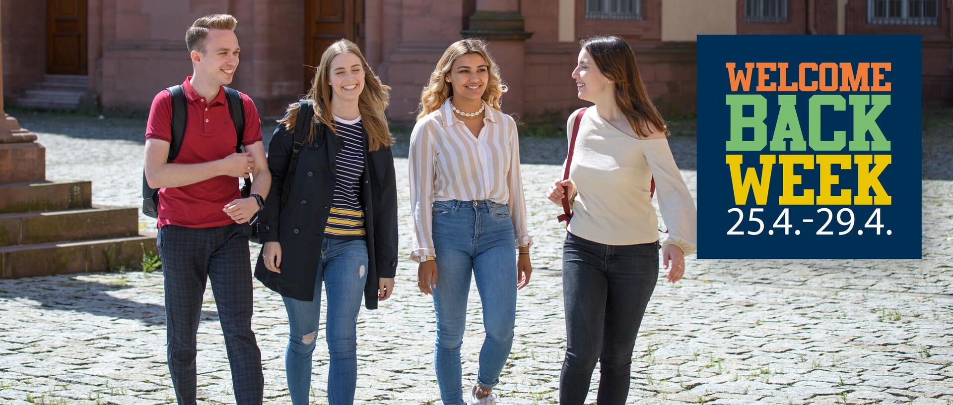 Vier Studierende laufen nebeneinander auf dem Ehrenhof, rechts im Bild ist der Schriftzug "WELCOME BACK WEEK".