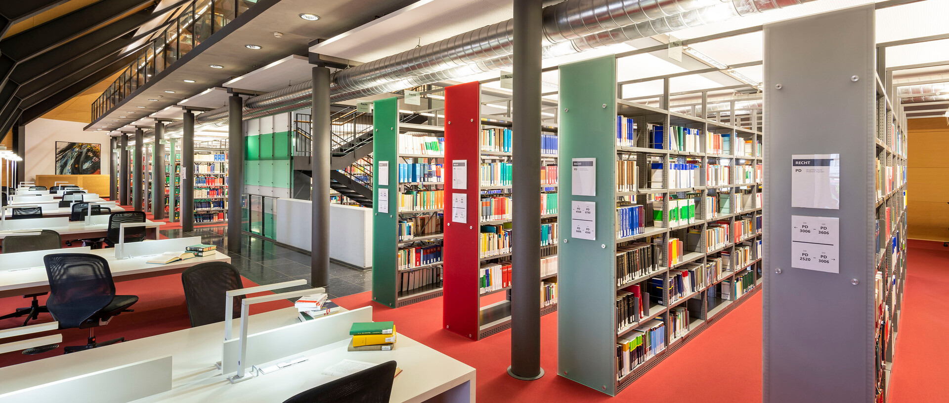 Dachgeschoss im Bibliotheksbereich Schloss Ehrenhof mit Schreibtischarbeitsplätzen und Bücherregalreihen.