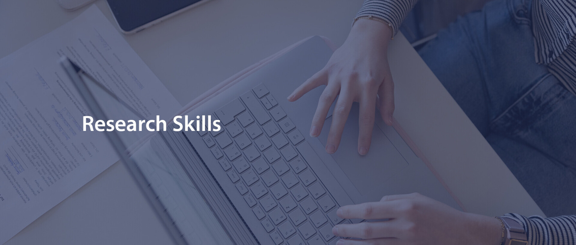 Eine Person schreibt am Laptop. Der Schriftzug "Research Skills" ist in weißer Schrift darübergelegt.