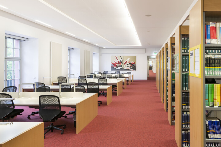 Bücherregalreihen und Arbeitsplätze im Bibliotheksbereich Schloss Schneckenhof.