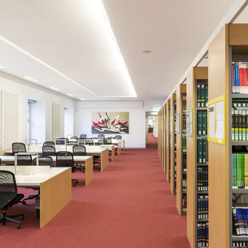 Bücherregalreihen und Arbeitsplätze im Bibliotheksbereich Schloss Schneckenhof.