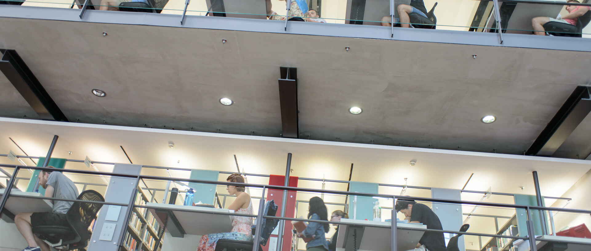 Blick auf die Galerie im Bibliotheksbereich Schloss Ehrenhof. Studierende lernen an Einzelarbeitsplätzen.